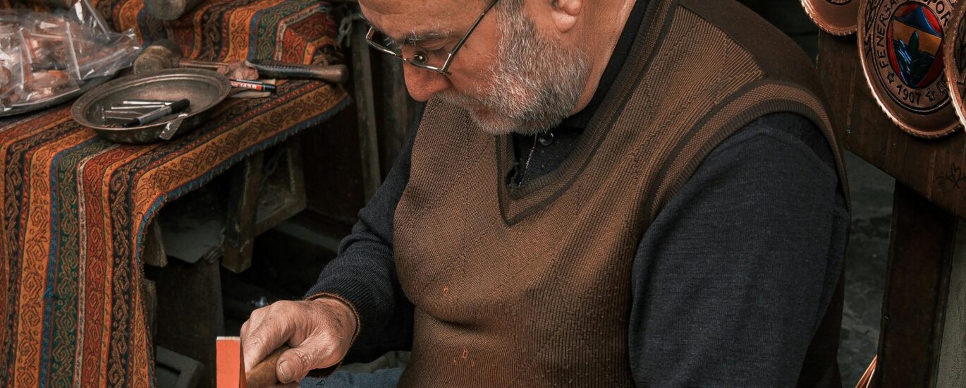 Skilled artisan carefully engraves copper plates in a traditional workshop setting.